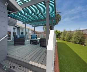 Shaded patio with large chairs and a table next to a green lawn.