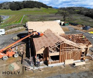 Wooden frame of a house being built surrounded by vineyards and trees