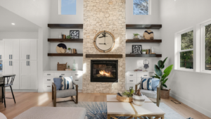 A fireplace in the middle of built-in shelves in a room with high ceilings and large windows.