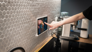 A person uses a smart screen in their kitchen to adjust the temperature.