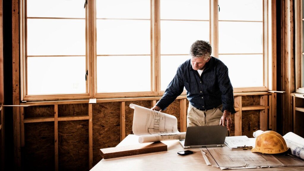 A home builder inspects his blueprints in a home build in progress.