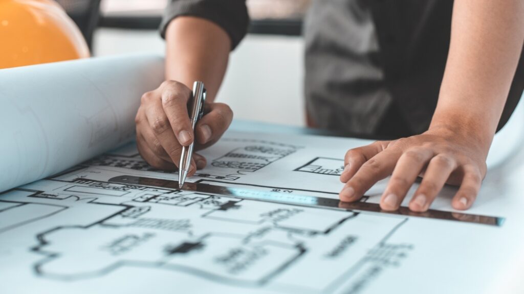 An architect uses a ruler and pen to draw a blueprint.