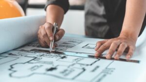 An architect uses a ruler and pen to draw a blueprint.