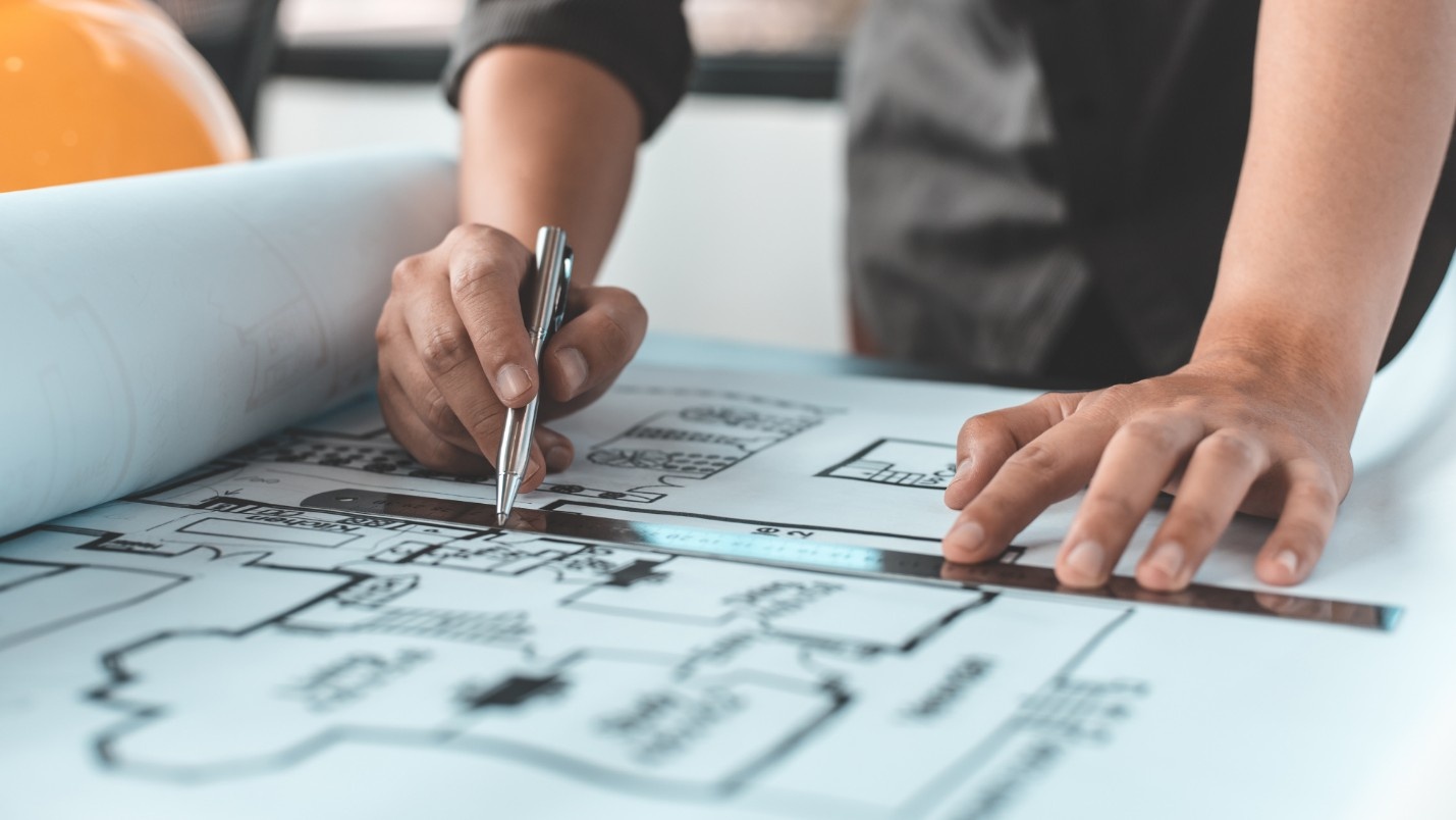 An architect uses a ruler and pen to draw a blueprint.
