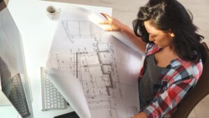 A female architect reviews the latest draft of a construction blueprint.