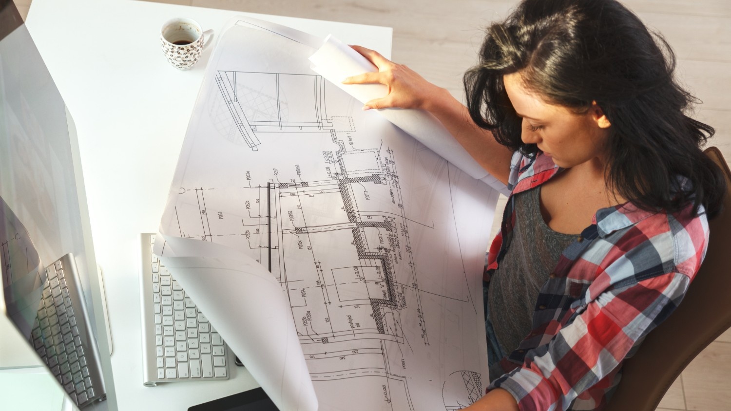 A female architect reviews the latest draft of a construction blueprint.