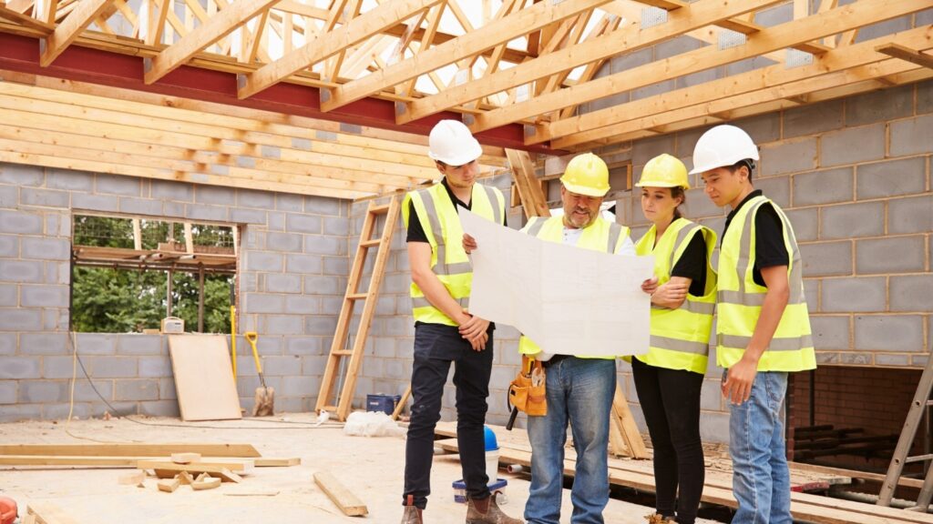 A small construction crew review a blueprint for a home build.