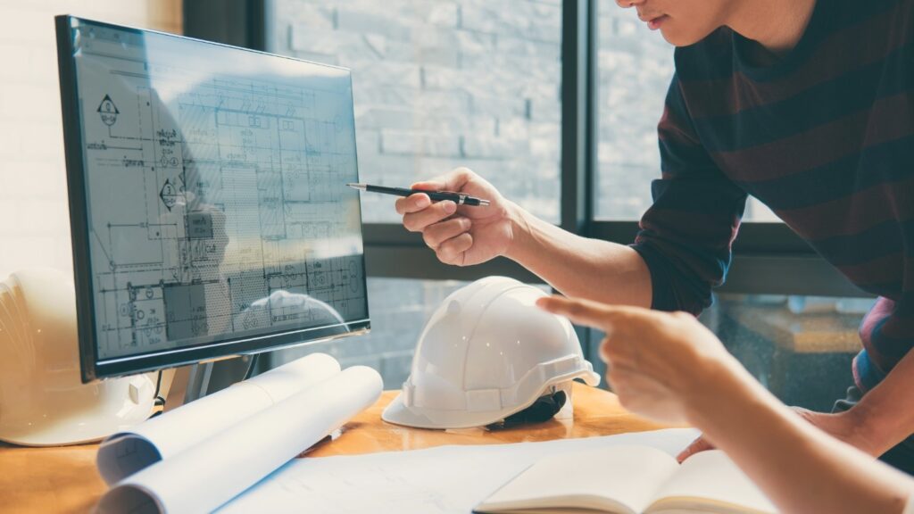 Two architects review blueprints on a computer screen.