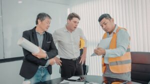 A project manager, school administrator, and contractor examine a document.