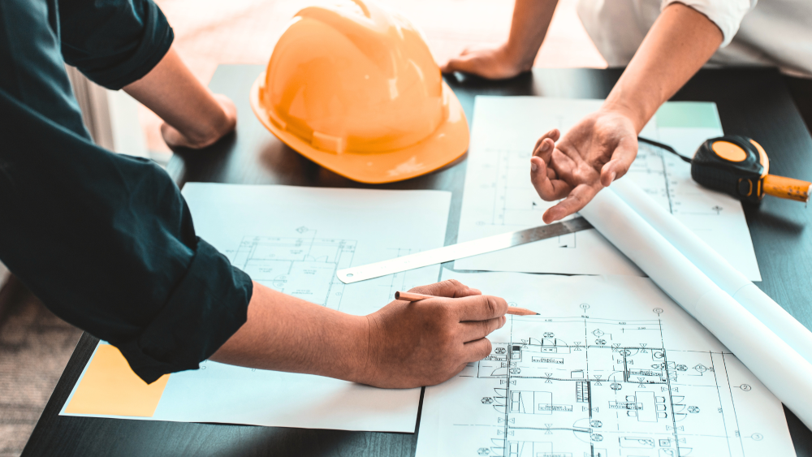 A general contractor meets with a custom home build client to go over the blueprints.